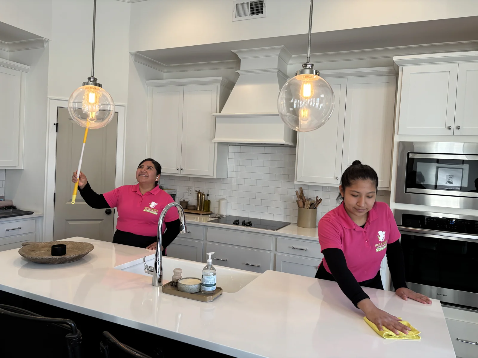 Hola Maids team carefully wiping a kitchen island in a client's home