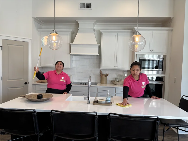 A Hola Maids team member wiping a white kitchen island